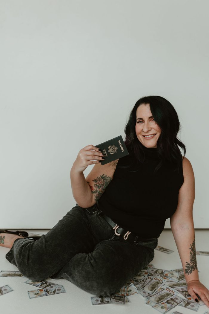 jami sitting around a bunch of money holding her passport make money, host retreats and travel the world